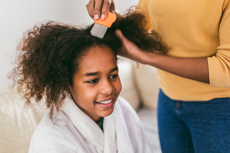 mom giving her daughter an at-home lice treatment