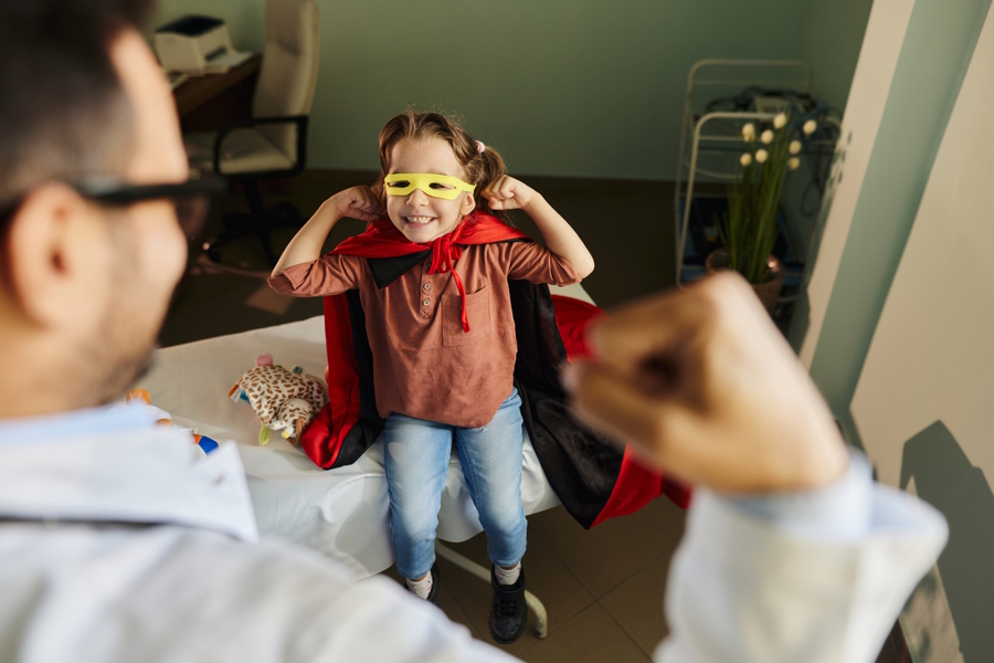 little girl dressed like a superhero standing in a room with her dad