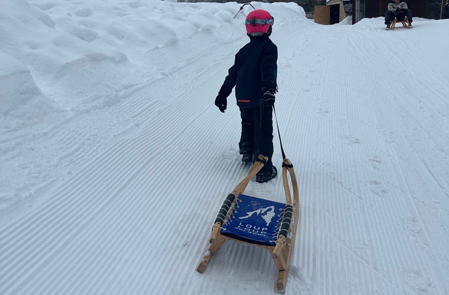 child walking with a sled in the snow at Loup Loup