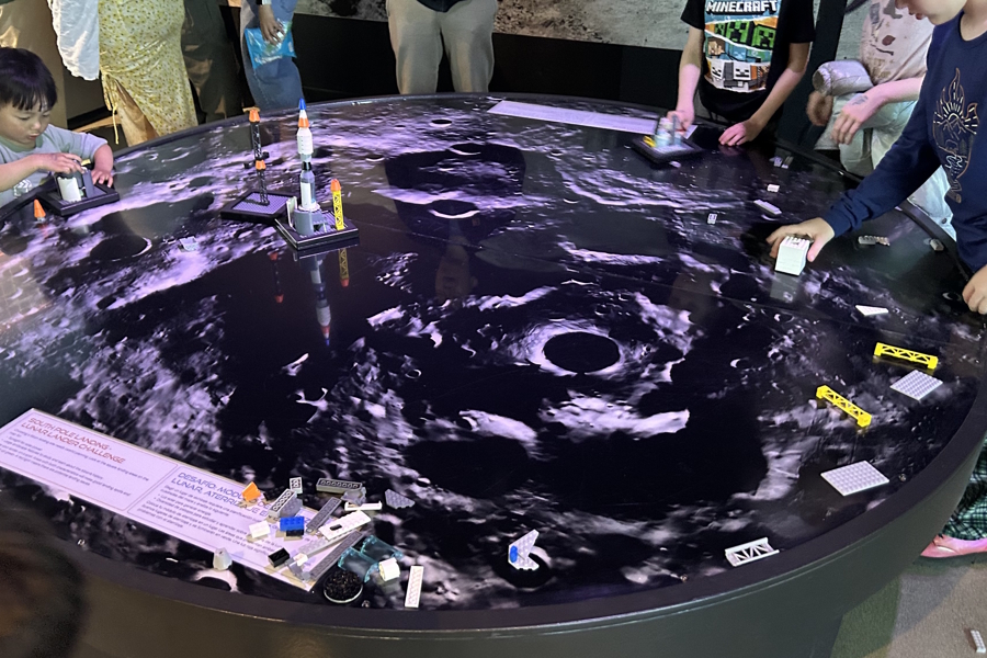 kids landing lego models on projection of the moons surface