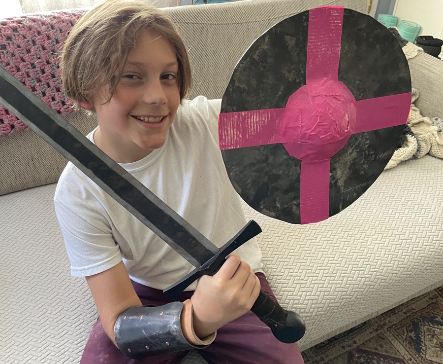 young boy with a shield and arm protector he made at a metal working class