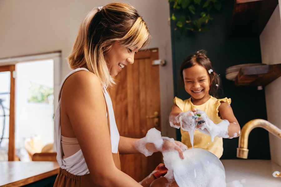 mom and daughter washing dishes and having fun together