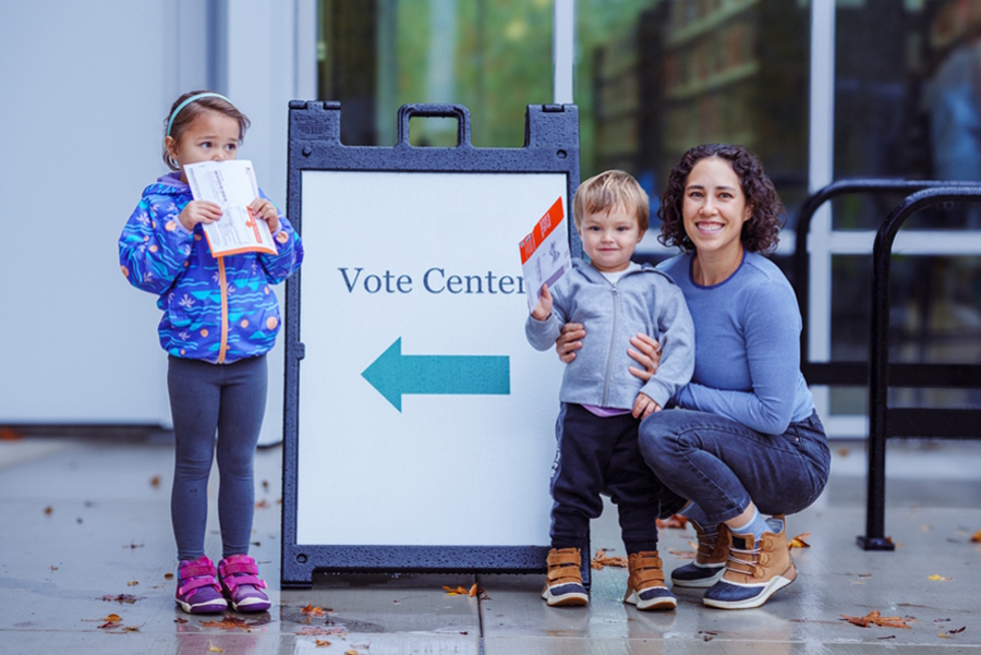 Mom and two young kids holding ballots