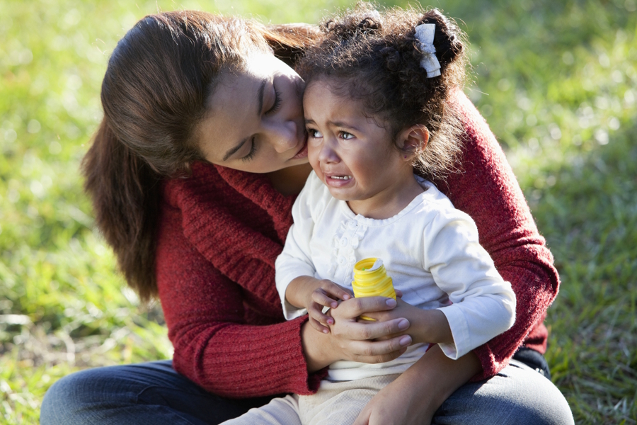 sad little girl sitting with her mom and crying