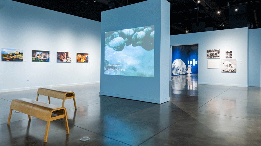 movie playing o the screen in "Tove and the Sea" exhibition with photographs on the wall