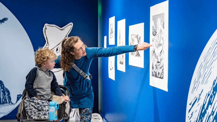 mom showing child the digital prints of moomin artwork in the exhibition at the National Nordic Museum