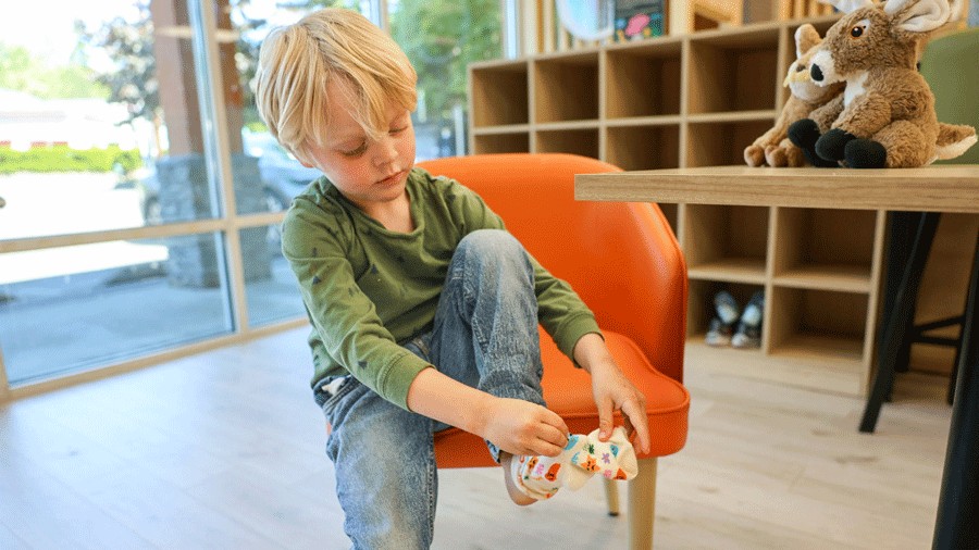 young kid putting on grippy socks next to the cubbies at Nixi City