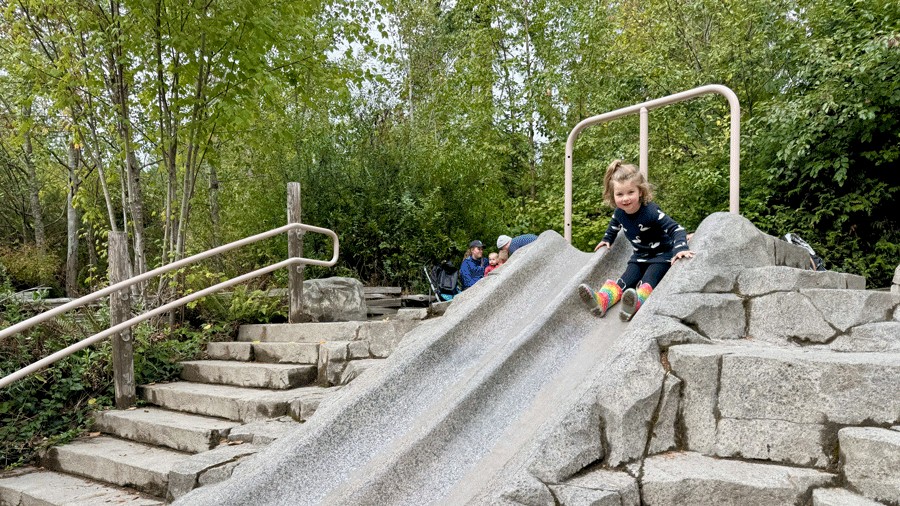 preschooler sliding down the concrete slide at Kids’ Trek