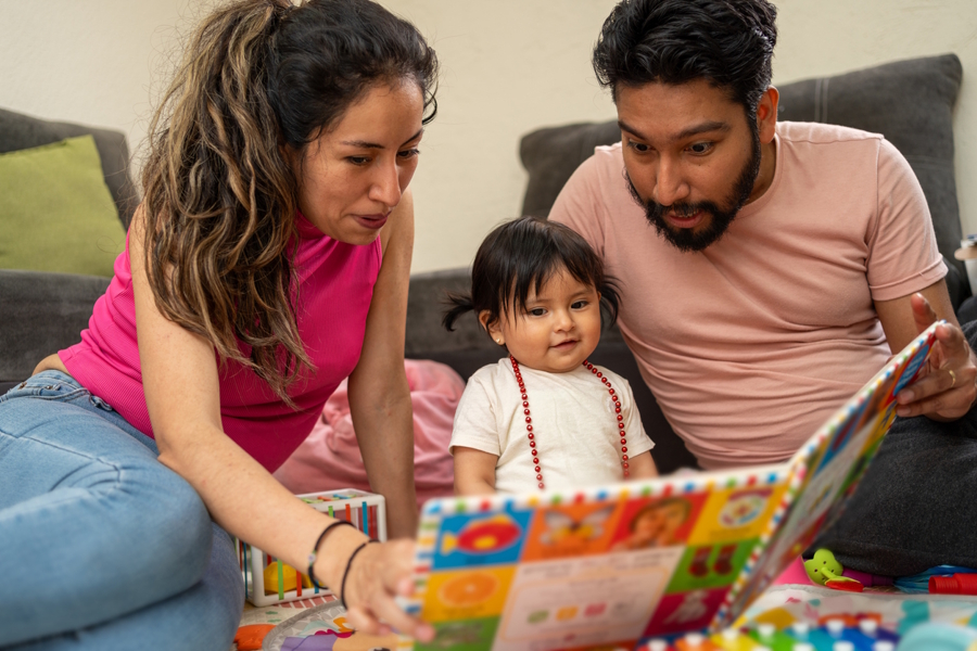 Two parents reading a book to their toddler daughter