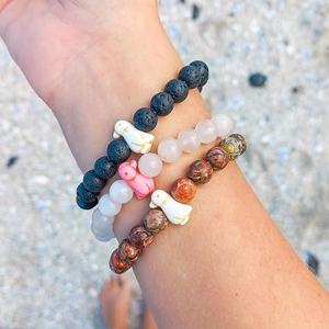 Penguin bracelets on a wrist over a beach