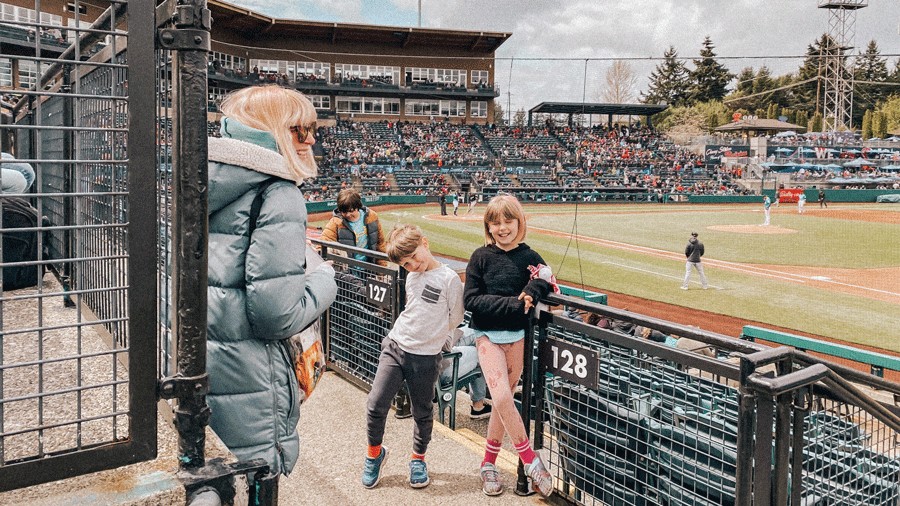 family smiling at Cheney Stadium during a ball game, a fun outing for families