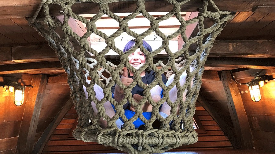 young child exploring the rope net climbing area inside the ship at Hands On Children's Museum