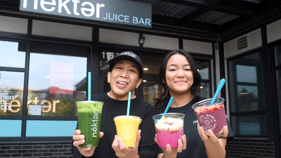 ownders of Nekter Juice Bar holding acai bowls and smoothies outside their redmond shop