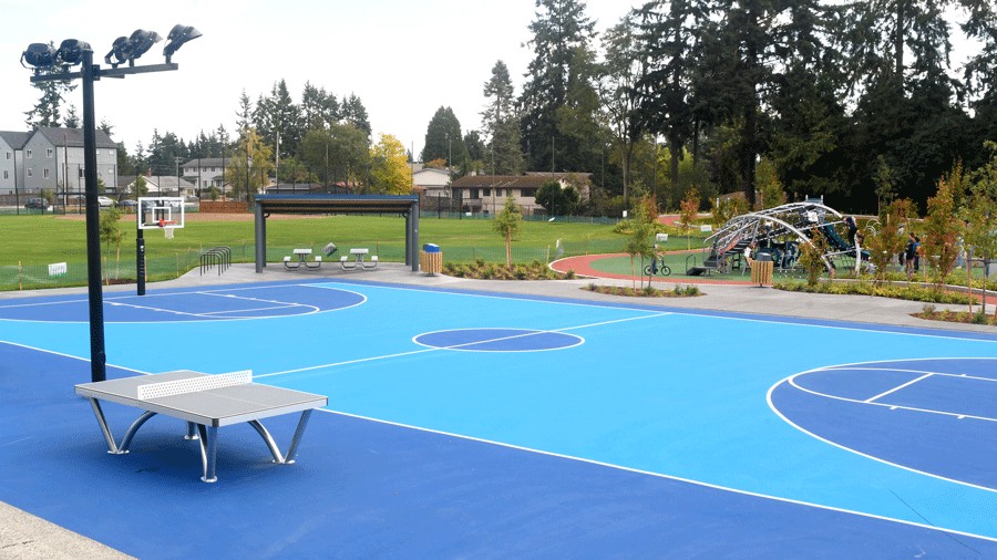 sport court and ball field at Richmond Highlands Park with playground behind it and kids playing