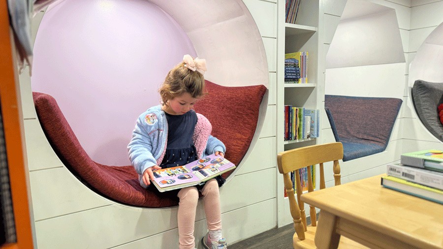young girl reading a book in the kids section at Joie Des Livres in Seabrook