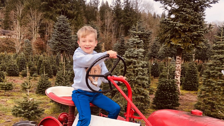 kid smiling on a tractor at Honeytree Farm, a local U-cut Christmas tree farm