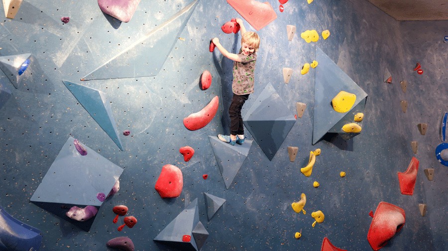 young kid bouldering at Seattle Bouldering Project on colorful walls