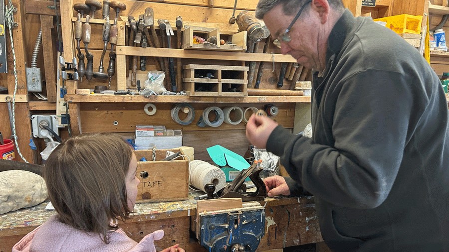 volunteer showing how to plane wood for boatbuilding at The Center for Wooden Boats