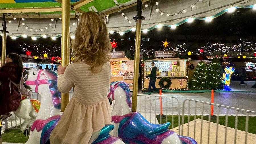 young kid riding a rainbow horse on the free carousel at Seattle Christmas Market