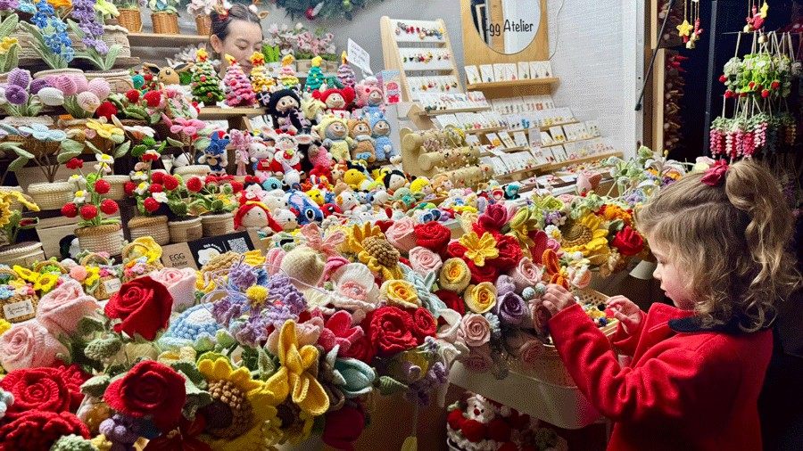 young girl looking at crocheted flowers at a Seattle Christmas Market vendor booth