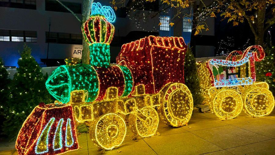 glowing holiday light display ith a train and santa's sleigh at Seattle Christmas Market