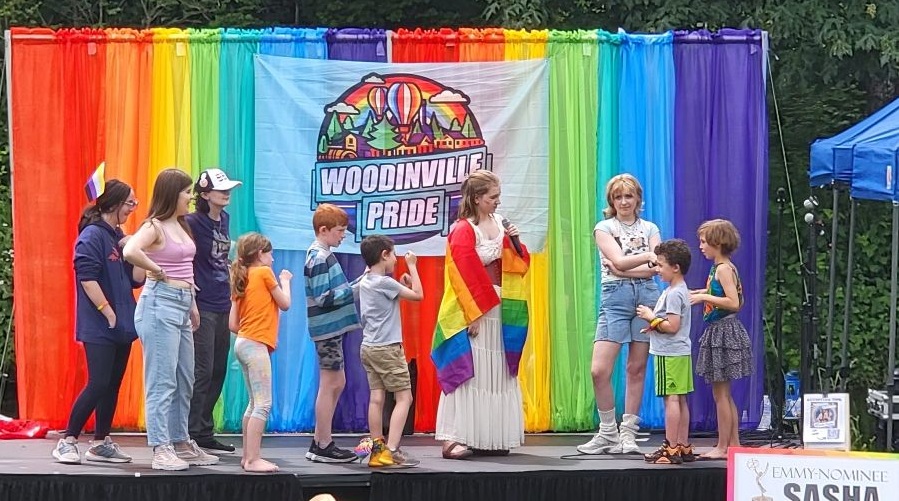 A group of kids line up on stage at a Pride celebration.