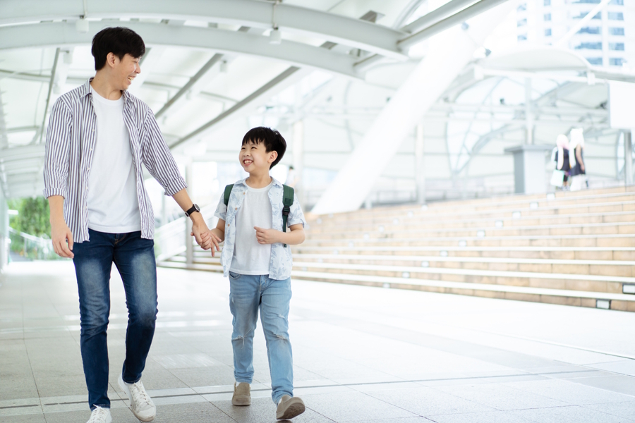 dad and son walking home holding hands and talking