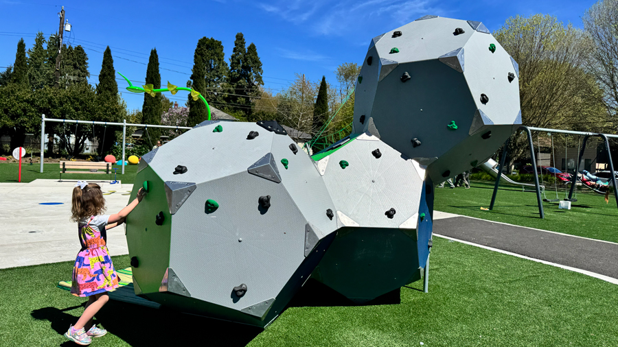girl reaching for climbing grip on a geometric structure at South Park Playground