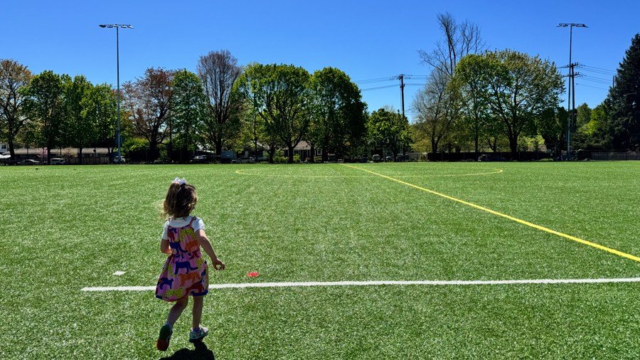 young girl on the playfield at South Park Community Center running toward a field line
