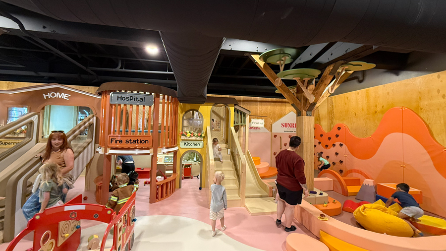 boy walking toward the steps of a play structure inside Sunrise Play Cafe
