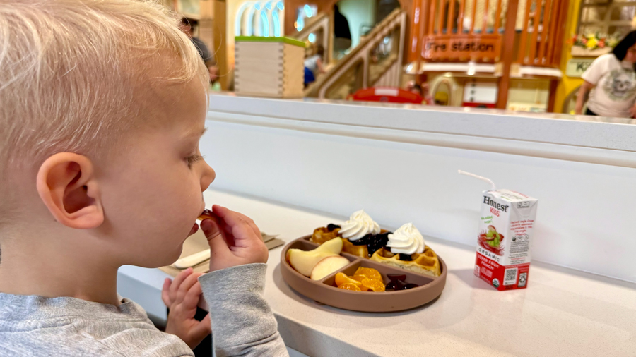 young child eating a kids meal at Sunrise Play Cafe with a juice box, waffle and fruit