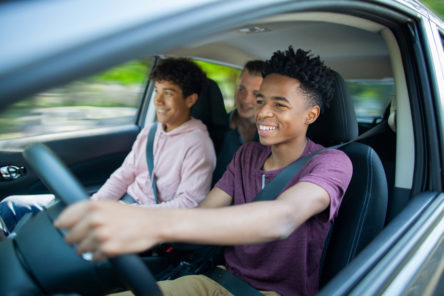 three teenage boys driving in a car 