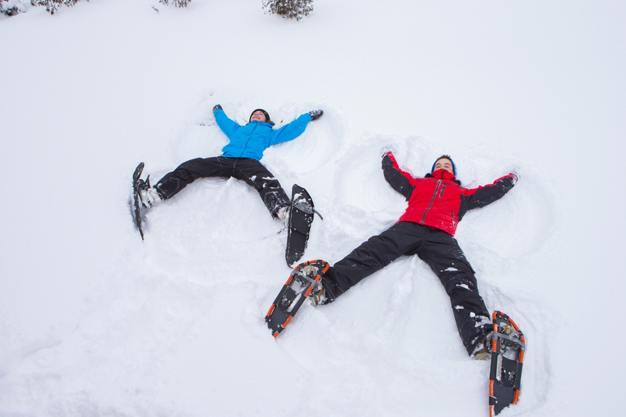 two kids making snow angels wearing snowshoes
