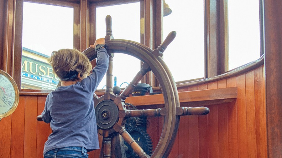young kid turning the wheel at the Maritime Museum, a fun thing to do with kids in Poulsbo