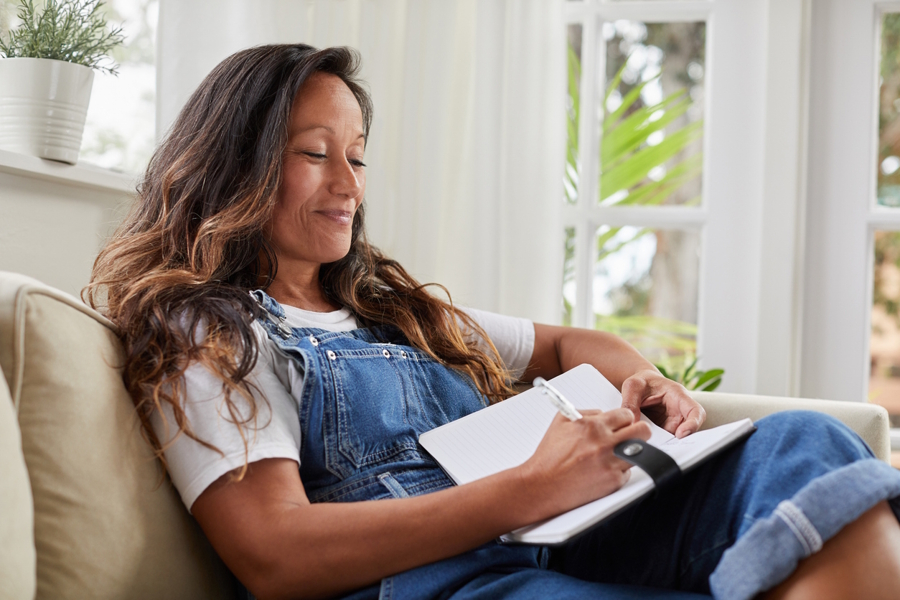 Woman sitting in a chair writing down things she is grateful for 