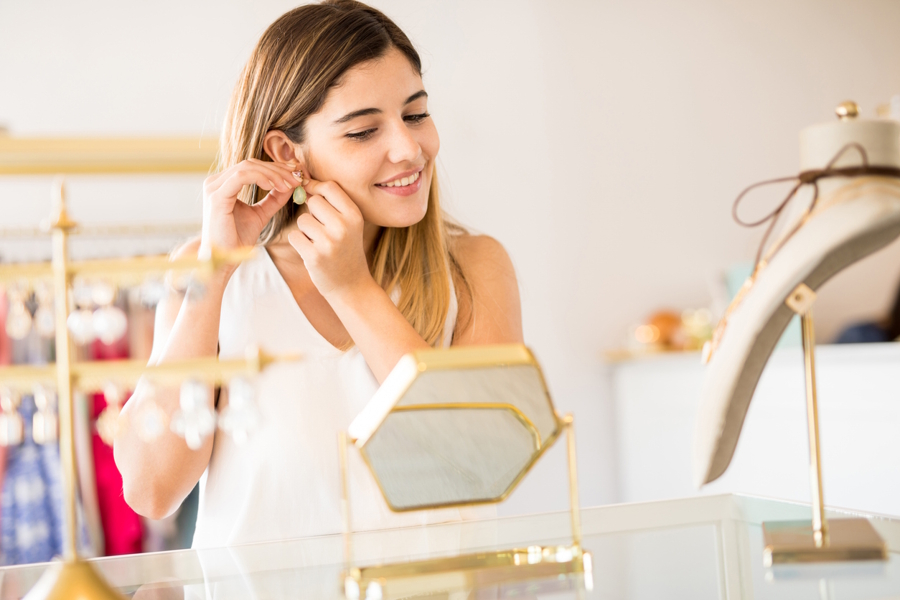 woman putting on earrings in a store