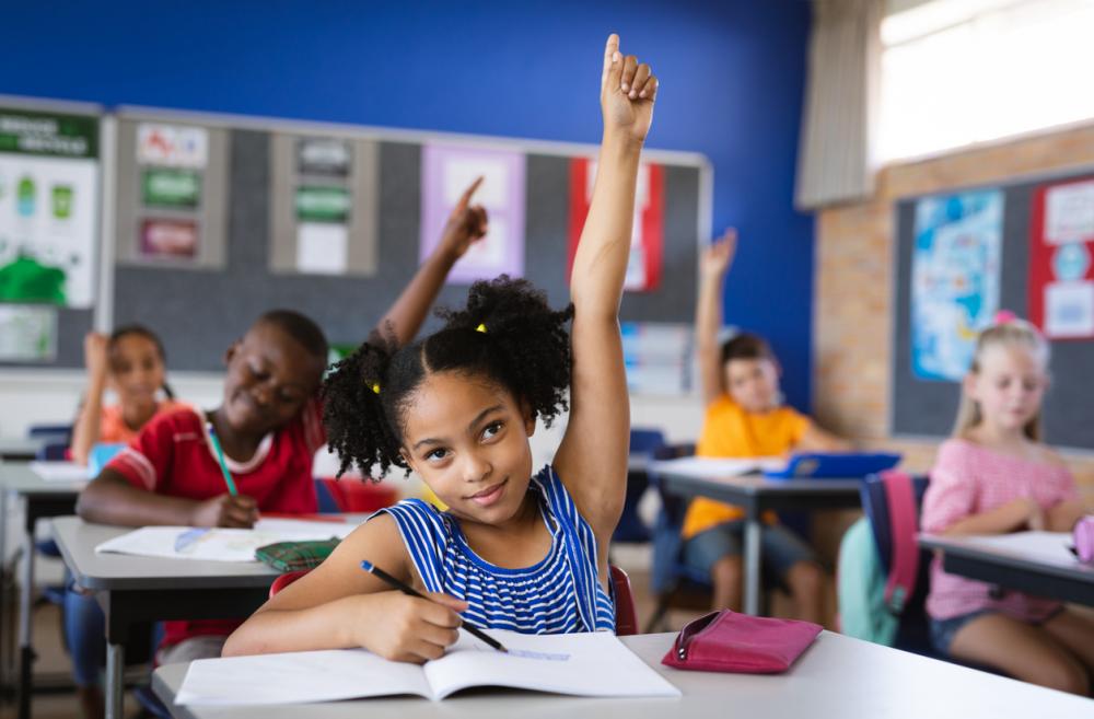 Young girl raising her hand in a classroom