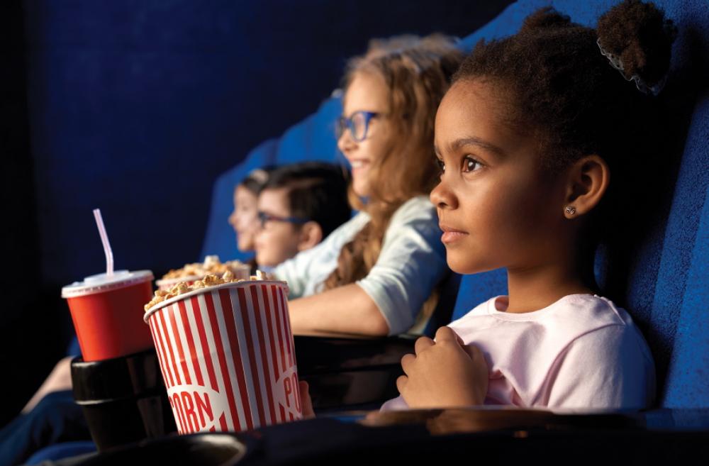 Kids watching a movie in a theater with popcorn