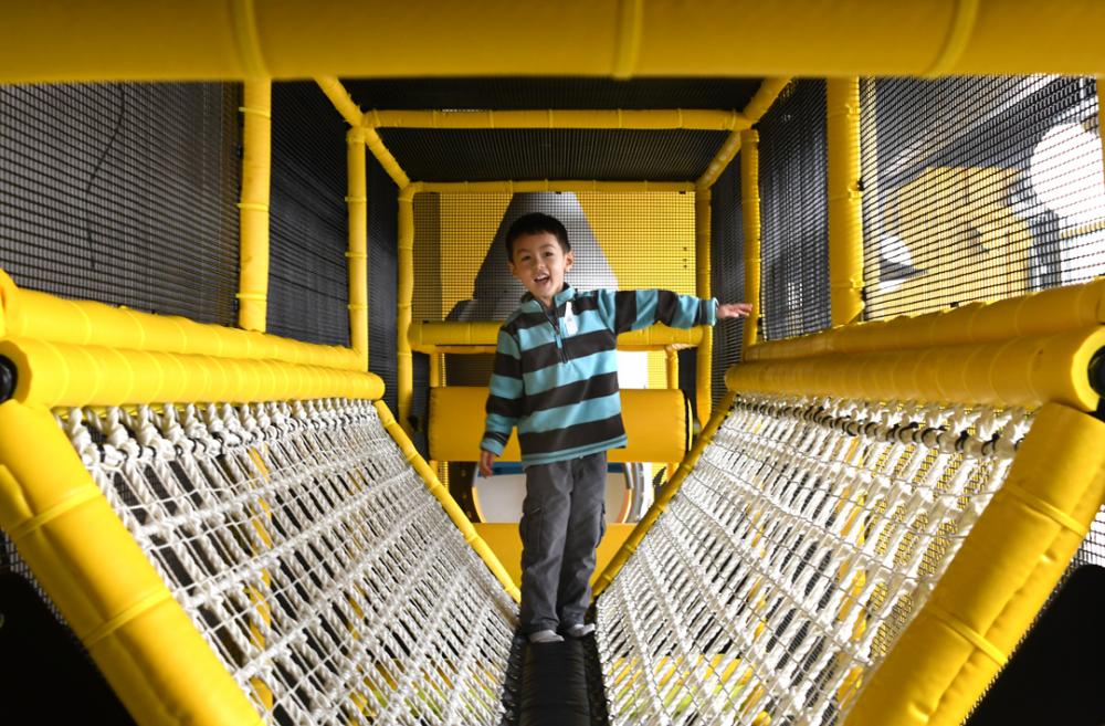 A young boy play in the climber at Outer Space Seattle, a West Seattle play space among many indoor play options for Seattle families on rainy days