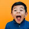 surprised happy little boy with a bright orange background
