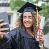 girl in a cap and gown taking a selfie alone