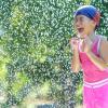 Girl running through the sprinkler, water play activity for summer