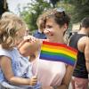 mother hugging her daughter at a pride parade with daughter holding the pride flag