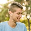 teen with acne scars smiling outdoors with headphones in his ears