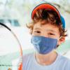 boy holding a tennis racket wearing a mask