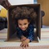 a child crawls through a cardboard box, part of an indoor obstacle course challenge