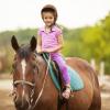 little girl riding a horse at horse camp