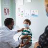 doctor listening to a child's heart with a stethoscope while the mom watches