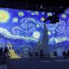 People look on as a digital projection of Van Gogh's Starry Night painting appears on the wall at Van Gogh: The Immersive Experience in Seattle