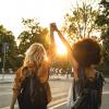Two young women -- one Black and one white -- walk together, holding each other's hand up high